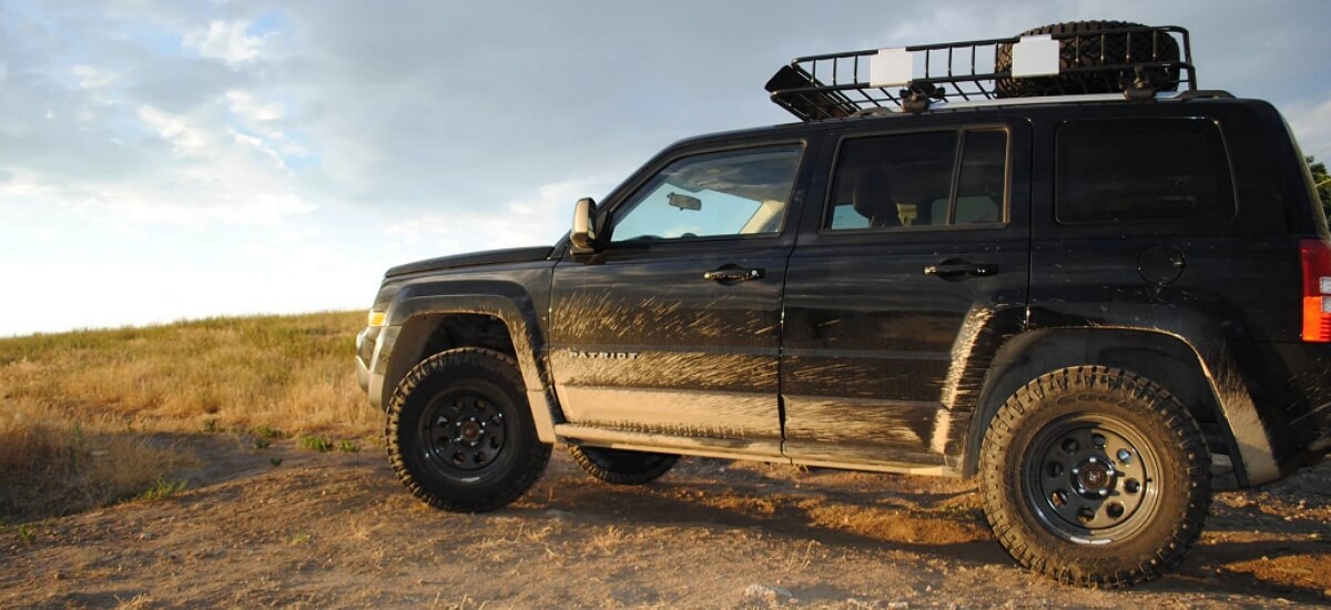 Black Lifted Jeep Patriot with mud tires and roof rack