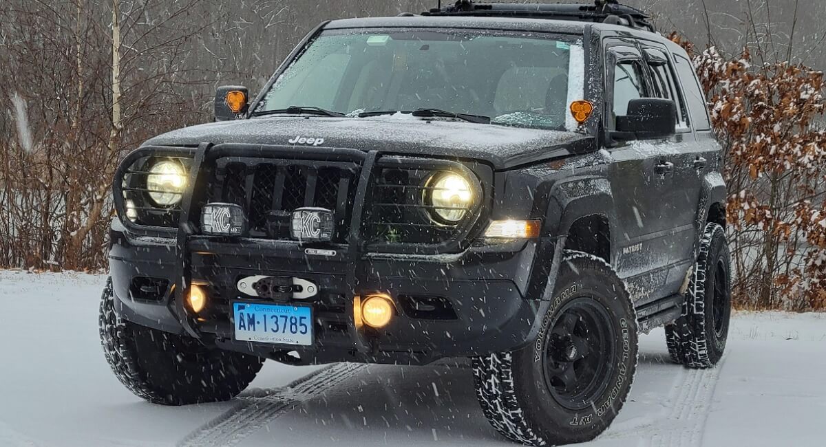 Jeep Patriot with an aftermarket grille guard, KC off-road lights and Yokohama snow tires