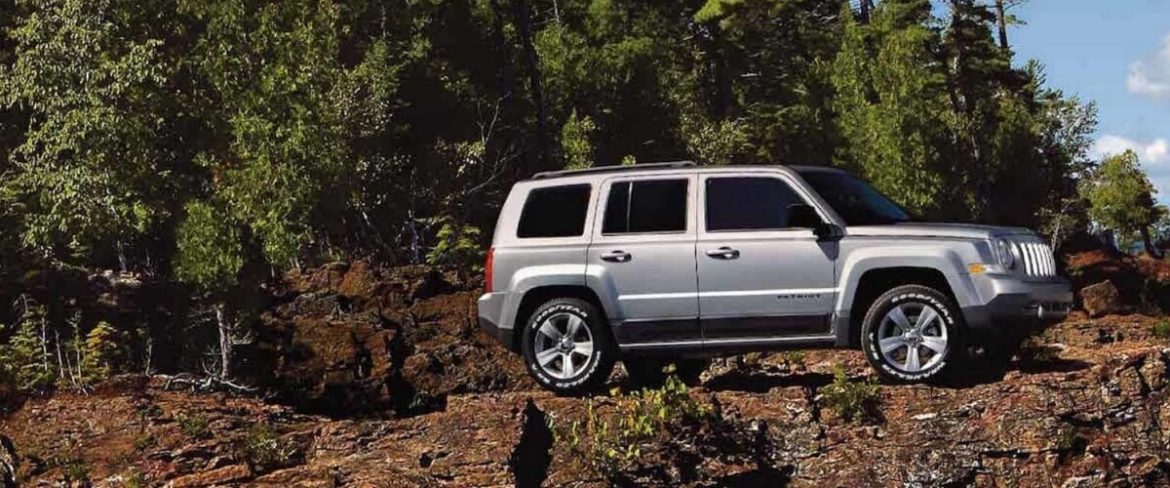 Jeep Patriot with off-road tires on rocky cliff